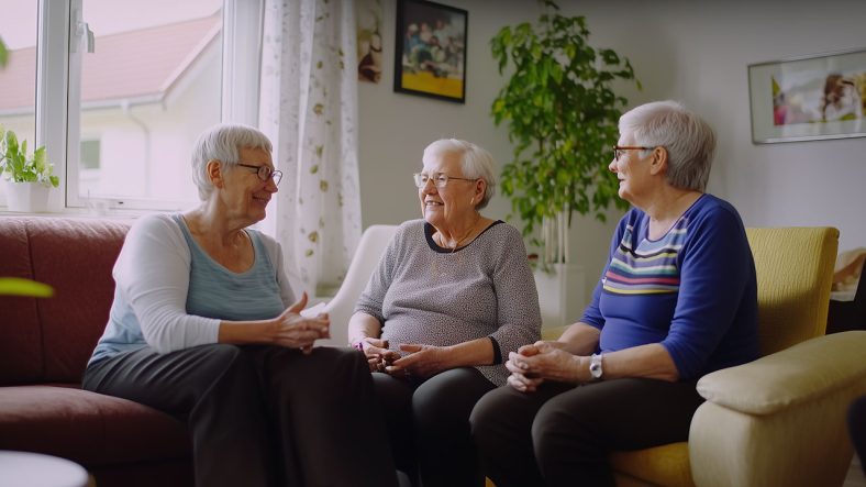 Tre kvinnor, pensionärer som sitter i soffa och pratar