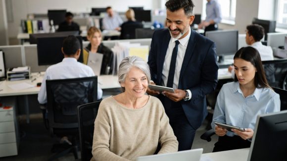 Senior kvinna i landskapsmiljö med yngre medarbetare. Foto: Grok