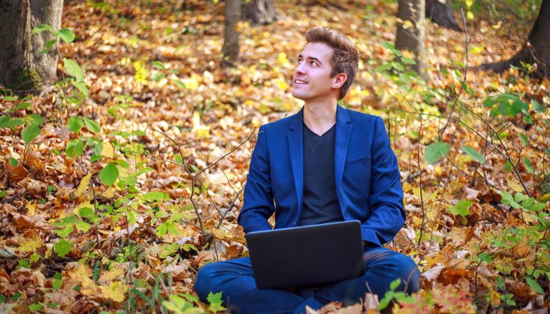 kille i kostym jobbar i naturen