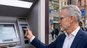 Äldre man tar ut pengar från bankomat. Foto: Gemini