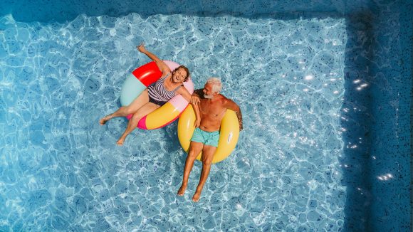 Ett pensionärspar som är i en pool i badringar.