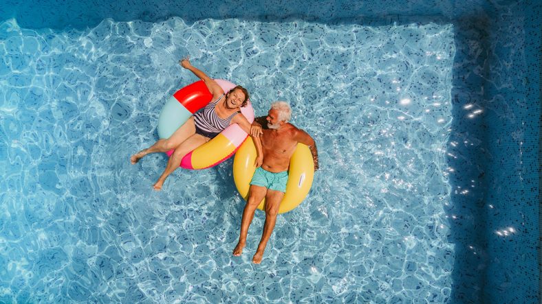 Ett pensionärspar som är i en pool i badringar.